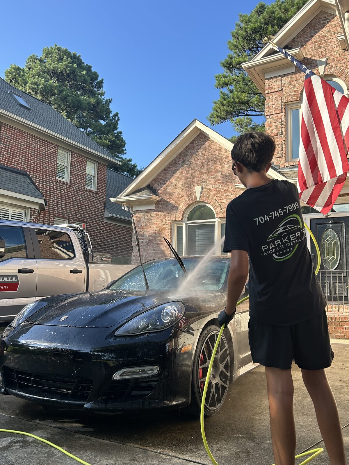 Parker's hand-washing a black Porsche Panamera in the driveway